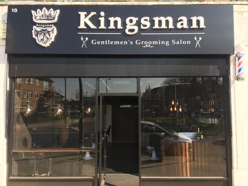 The black shopfront of the salon at street level, with a glass door and a barber's pole to the right